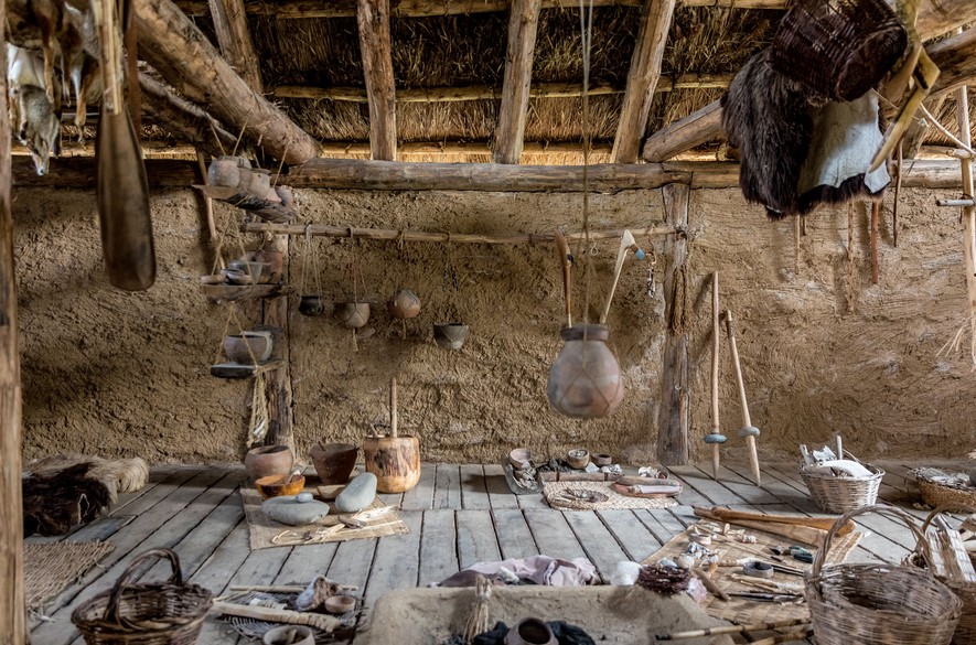 Why were Neolithic villages built on hilltops or river terraces?